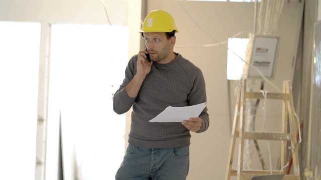 Architect wearing helmet and talking about the project on cellphone, steadycam shot

