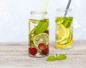 Citrus, cherry and herbs infused sassi water for detox or dieting in glass bottles. Clean eating, weight loss, healthy lifestyle concept