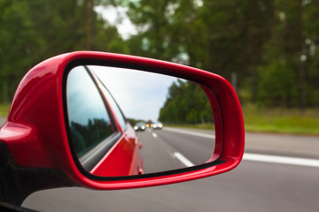 Highway Rear View / View back to road through red side mirror at car