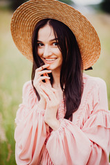 Cheerful brunette woman in pink dress and hay hat