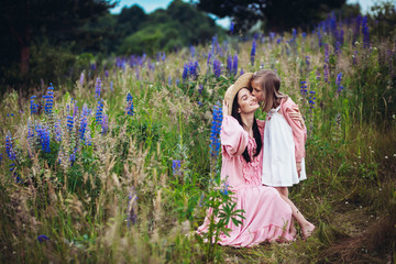 Woman and little girl in pink dresses pose on the field of lavander