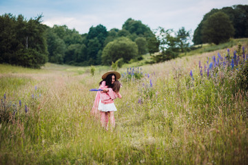 Mom and daughter in pink dresses run barefooted on the field