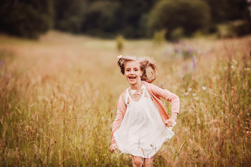Little girl in white dress runs on the green field
