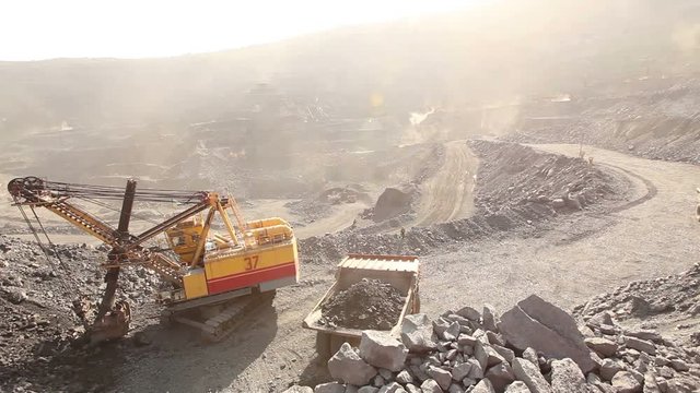 Industrial excavator and working man in a quarry, a large jaded industrial excavator