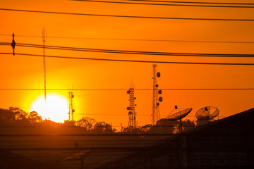 Cell tower and city buildings at sunset