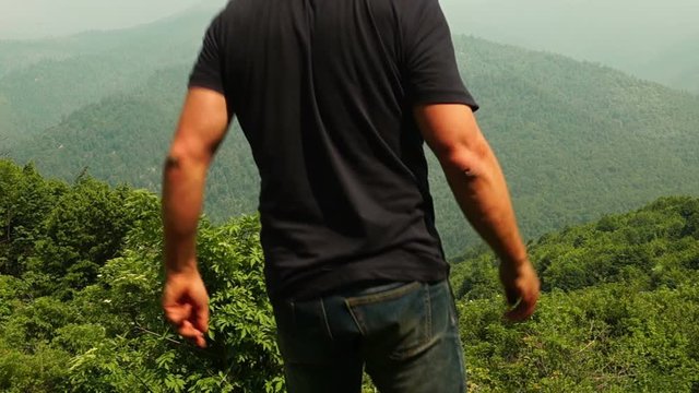 Man looking around and raising hands up in awe of the mountains