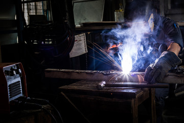 Welder working a welding metal with protective mask and sparks