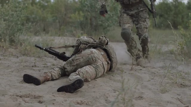 Slow motion Commander takes away from under firing of the soldier in the field of fight