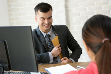 Businessman putting envelope into his suit pocket while making an agreement
