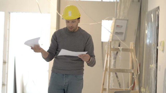 Architect looks worried while checking project about new flat, steadycam shot
