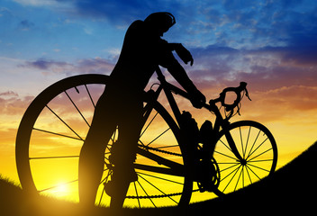 Silhouette of a cyclist on a road bike at sunset.