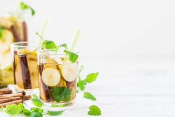 Refreshing drink with pear, cinnamon on white table. Copy space