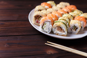 Tasty great colorful set of fresh japanese sushi maki rolls served on round plate,with chopsticks, close up. Food art, traditional seafood, restaurant menu photo