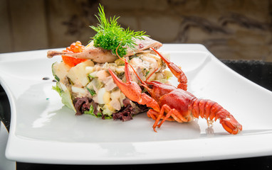 Olivier salad with trout in a white plate.