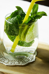 Cold pure carbonated water with lime in a glass on a light background. Selective focus. Vertical.