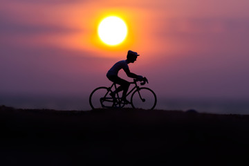 Silhouettes model of cyclists on the beach with sunset.
