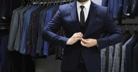 Elegant business man in white shirt correcting his tie and buttoning his suit jacket. close up