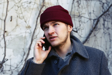 Busy young man in red hat talks on the phone