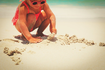 hands of little girl play with sand on beach