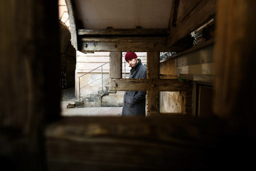 Look through wooden blocks at young man in grey coat