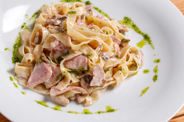 Tagliatelle pasta with ham, mushrooms and yolk. Selective focus