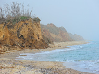 Foggy sea cost with sandy cliff