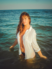 A young  American girl with curly hair  resting on the ocean coast and having a great weekend,...