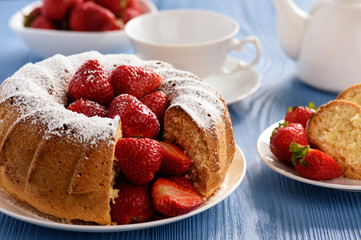 Homemade cake with strawberries on wooden background.