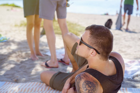 Young man with tattoos relaxing on a beach