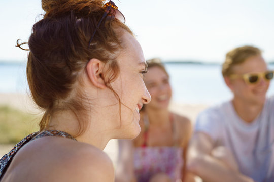 Young woman chatting with friends on the beach