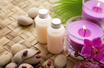 Fototapeta na wymiar SPA still life. cosmetic bottles, aromatherapy candles, orchid flowers and pebbles