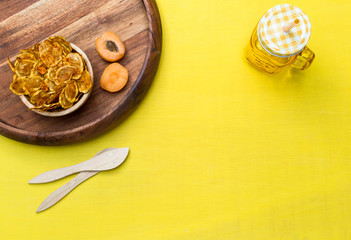 Fototapeta na wymiar Blank yellow tabletop scene with zucchini chips and apricots
