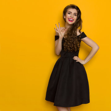 Smiling Elegant Woman In Black Dress Is Showing Ok Hand Sign
