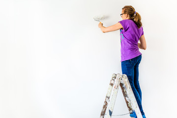 Painting wall using paint brush, working indoors, home renovation concept