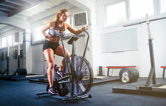 Woman at crossfit gym using exercise bike for cardio workout