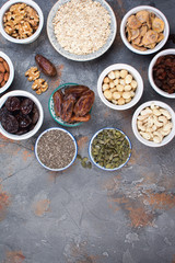 Ingredients for homemIngredients for homemade granola, oats, different nuts and raisins, dates, seed on the grey stone background, top viewade granola on the grey