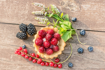 Different berries in a basket of dough and twigs with mint colors on an old brown cracked background. Natural sunlight.
