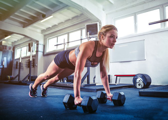 Fitness woman working out with dumbbells doing push ups training