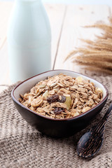 Breakfast cereals with dried fruits in a bowl on a wooden background.