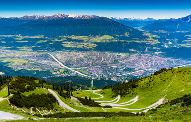 view from above of Innsbruck city with alpes mountain range, Natural path and Cable car take from Nordkette mountain - obrazy, fototapety, plakaty