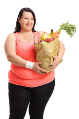 Overweight woman holding paper bag filled with fruit and vegetables