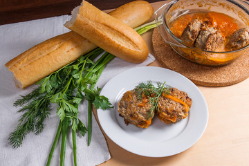 Rissole of pork served on a white plate with white wheat bread and herbs - dill, green onion, parsley around the plate.