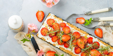 Home made strawberry not baked cheese cake in oven tin on gray background with flowers