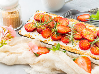 Home made strawberry not baked cheese cake in oven tin on gray background with flowers