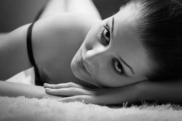 sensual beautiful girl lying on white fur looking at camera, monochrome