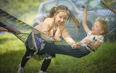 Little children siblings having fun on a swing net in a park
