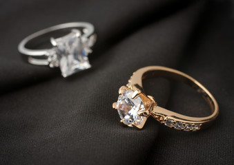 two jewelry rings with diamonds on black cloth, soft focus