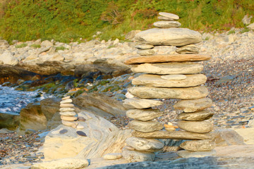 Zen rock balancing statue built with natural rocks near the ocean. Shot at sunrise