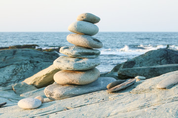 Zen rock balancing statue built with natural rocks near the ocean. Shot at sunrise