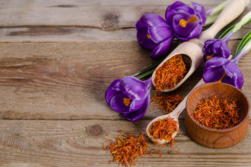 crocus flowers and spoon with soffron  on wooden table